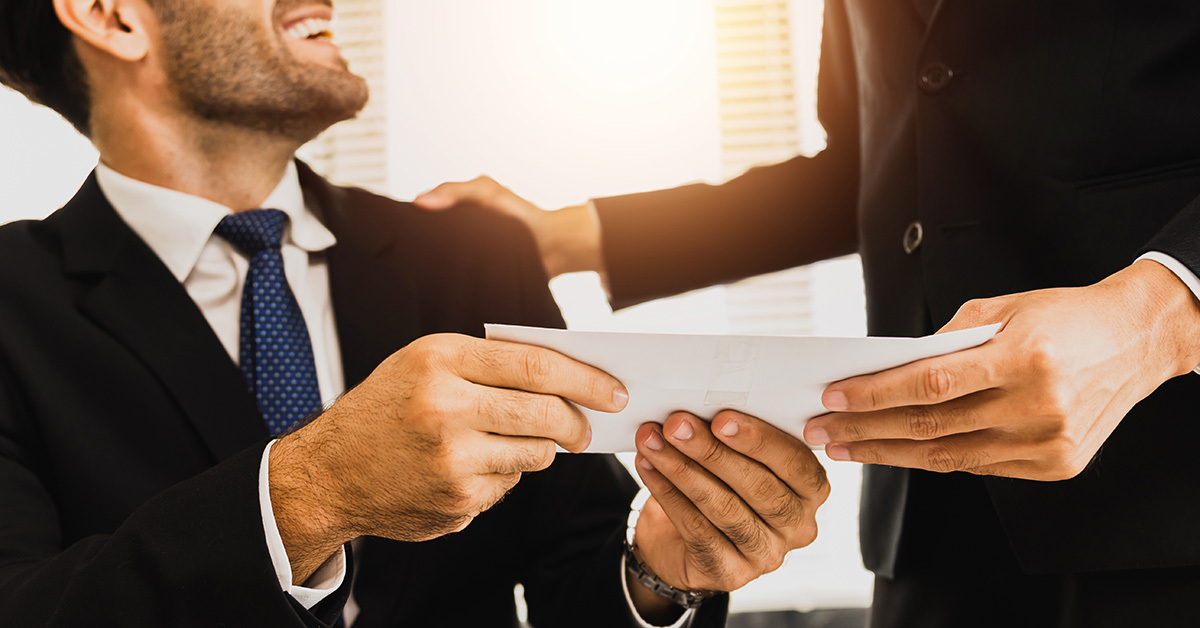 Two business professionals in suits passing an evenlope between them